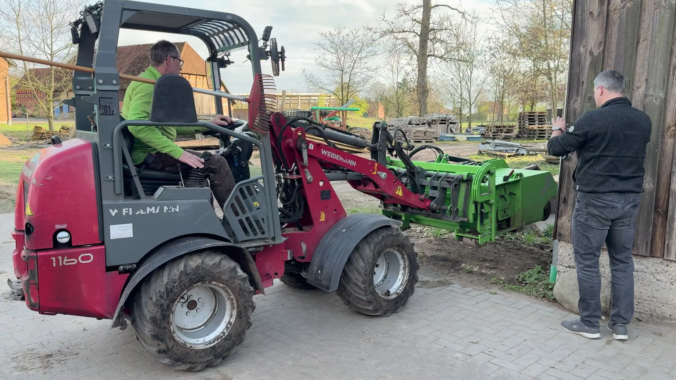 Johann Krahfuß am Hoflader und Oliver Groht neben dem montierten FARM-SERVANT ECO bei einer Gerätevorführung auf dem Hof