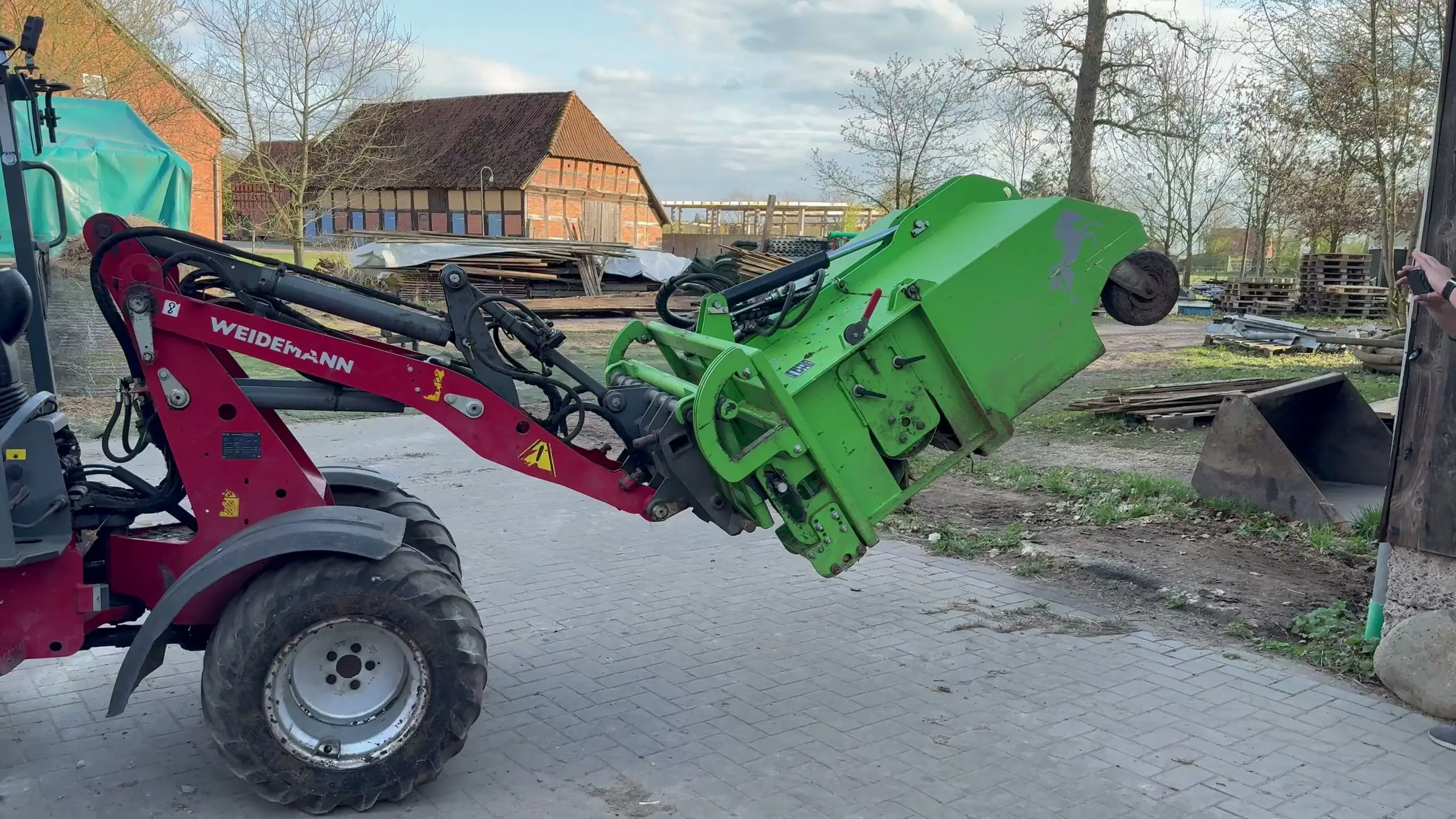 FARM-SERVANT ECO angehoben und gekippt am Hoflader, im Hintergrund der Hof